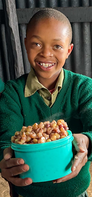 A student holdeing a bowl of githeri.