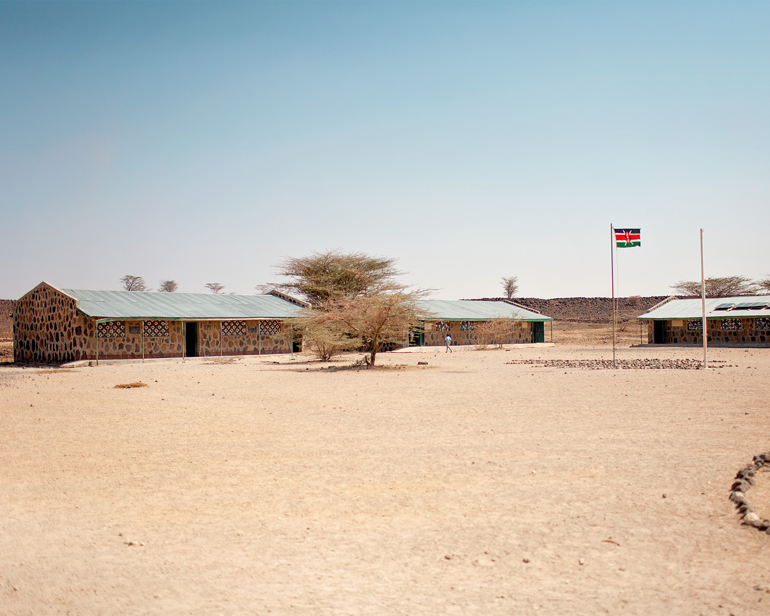 stone school buildings and Kenyan flag